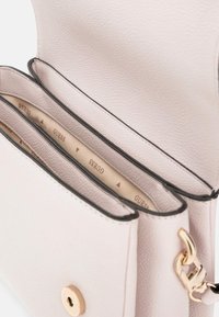 Rosa strukturierte Handtasche mit goldener Hardware, die zwei offene Fächer und ein gebrandetes Innenfutter aufweist.
