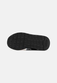 Semelle de chaussure en caoutchouc noir avec motif de grip texturé et logo Adidas. Le design présente une forme plate et large pour plus de stabilité.