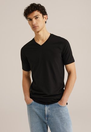 T-shirt nera a maniche corte e scollo a V, realizzata in tessuto morbido, abbinata a jeans di denim blu chiaro. La maglietta ha una vestibilità comoda e dettagli minimi.