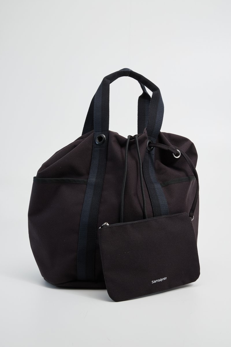 Bolso de mano negro de lona con forma redondeada, asas oscuras en contraste y un estuche con cremallera desmontable. Textura mate, diseño sencillo y costuras destacadas.