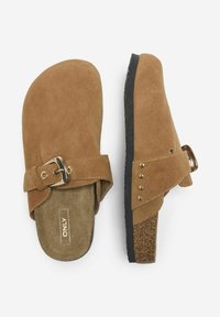Sandali slip-on in suede marrone con cinturino a fibbia, soletta texturizzata e piccoli chiodini decorativi lungo il lato. Suola nera e dettagli in sughero.