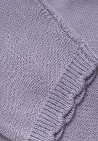 Lila gebreide stof met fijne en ribbelige texturen en een gekartelde randafwerking. Soepele en lichte stof. Close-up weergave.