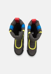 Izolowane buty z wyściółką w kolorze szarym, jasne żółte akcenty oraz niebieskie i czerwone paski. Czarna podeszwa o teksturowanej powierzchni.