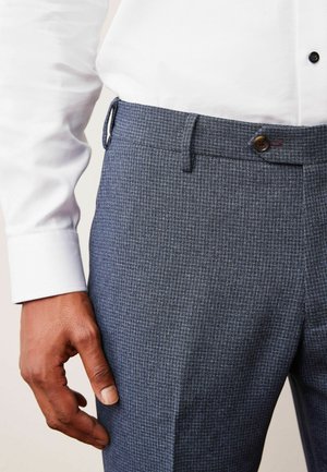 Pantalons à carreaux gris moyen en tissu texturé, avec une coupe droite, une taille avec passants de ceinture, et une fermeture à bouton à l'avant.
