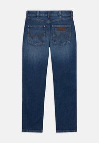 Jeans de mezclilla azul oscuro con un corte recto, que presentan dos bolsillos traseros con costura en zigzag y una etiqueta de cuero en la cinturilla.