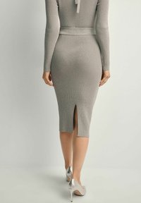 Sukienka z długim rękawem, prążkowana, w kolorze szarym, z rozporkiem z tyłu, z dopasowaną talią i gładką fakturą. Połączona z metalicznymi szpilkami.