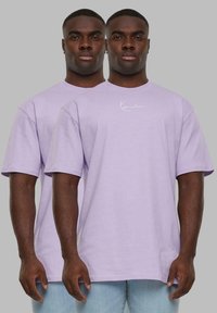 Levendula rövidujjú póló kerek nyakkal és fehér logóval a mellrészen. Az anyag lágy és enyhén textúrázott. Unisex dizájn.