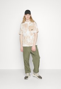 Nike Sportswear Triko s potiskem - beige/black
