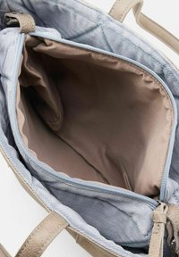 Beige handtas interieur met lichtblauwe stoffen voering, ritsafsluiting en gladde textuur. Bevat tan kleurige hengsels en gevoerde zijkanten.
