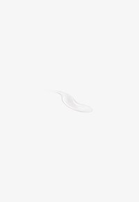 Petite noisette de crème ou lotion blanche sur une surface blanche avec une texture lisse et une légère ombre.