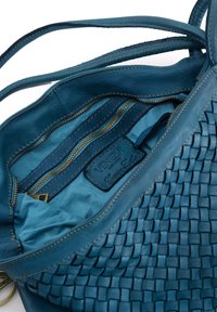 Geweven leren handtas in teal met een gladde binnenvoering, voorzien van ritszakken, een hoofdcompartiment en een gelabelde leren tag.