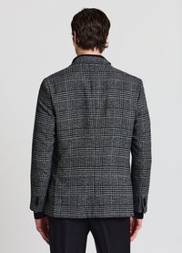 Blazer a quadri in tessuto nero e grigio, con vestibilità sartoriale, rever a incavo e polsini neri a contrasto.