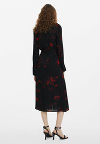 Must mustriga mustriga punaste lilledega, pikkade varrukatega, vöödiga taljes ja keskmise pikkusega hemiga. Kandmine mustade rihmadega kontsadega. Transparantne tekstuur.