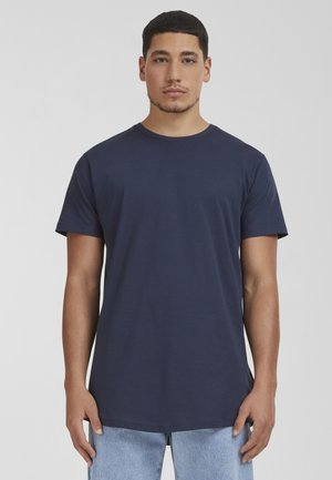 T-shirt in cotone blu navy con scollo rotondo, maniche corte e orlo dritto, indossata da un modello su uno sfondo neutro.