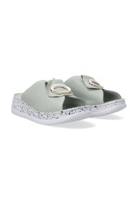 Lichtgroene instapsandalen met perforated bovenkant, cirkelvormige hardwareaccent en gespikkelde witte zool. Glad materiaal met een vlak ontwerp.