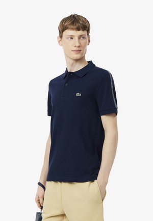 Marineblauw poloshirt van katoen met korte mouwen, een twee-knops sluiting en een groen krokodillenlogo op de borst.