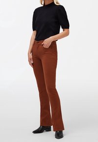 Jean marron évasé avec une texture lisse, taille mi-haute et design à cinq poches, associé à un haut ajusté à manches courtes noir.