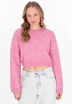Roze cropped sweater van zacht, textuur gebreid met lange mouwen en geribbelde zoom, gecombineerd met licht gewassen high-waisted jeans.