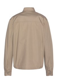 Camicia a maniche lunghe color marrone chiaro con colletto, polsini bottonati e orlo arricciato. Tessuto liscio con un colore uniforme e dettagli minimi.