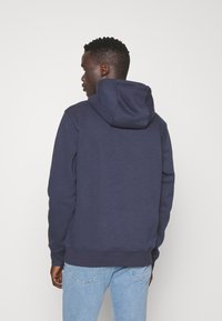 Sudadera azul marino hecha de una suave mezcla de algodón, con capucha ajustable, mangas largas y puños y dobladillo de canalé.
