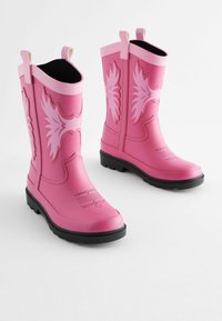 Růžové gumové deštník boots se zdobnými světle růžovými vzory, černou texturovanou podrážkou a poutky na vršku pro snadné obouvání.