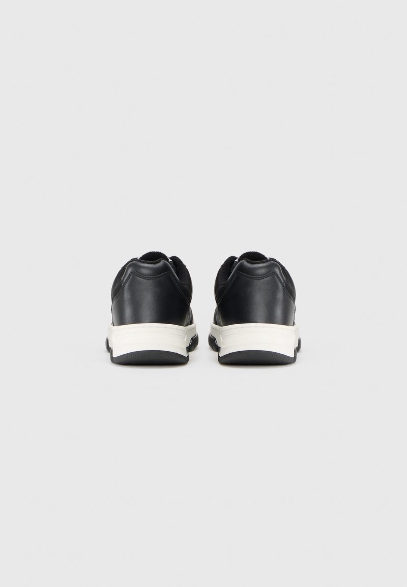 Schwarze Ledersneaker mit runder Form, weißer Gummisohle und strukturierten Details an der Ferse. Die Rückansicht zeigt einen gepolsterten Schaft.