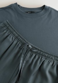 Czarnoszary t-shirt z okrągłym dekoltem i krótkimi rękawami, zestawiony z wygodnymi, czarnoszarymi szortami na elastycznej talii z sznurkiem.