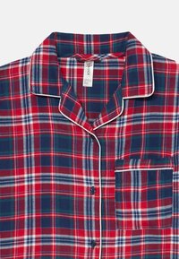 Punane ja tumesinine ruuduline ööpaita, valmistatud pehmest kangast, millel on lõigatud krae, valge ääris ja üks rindkere tasku.