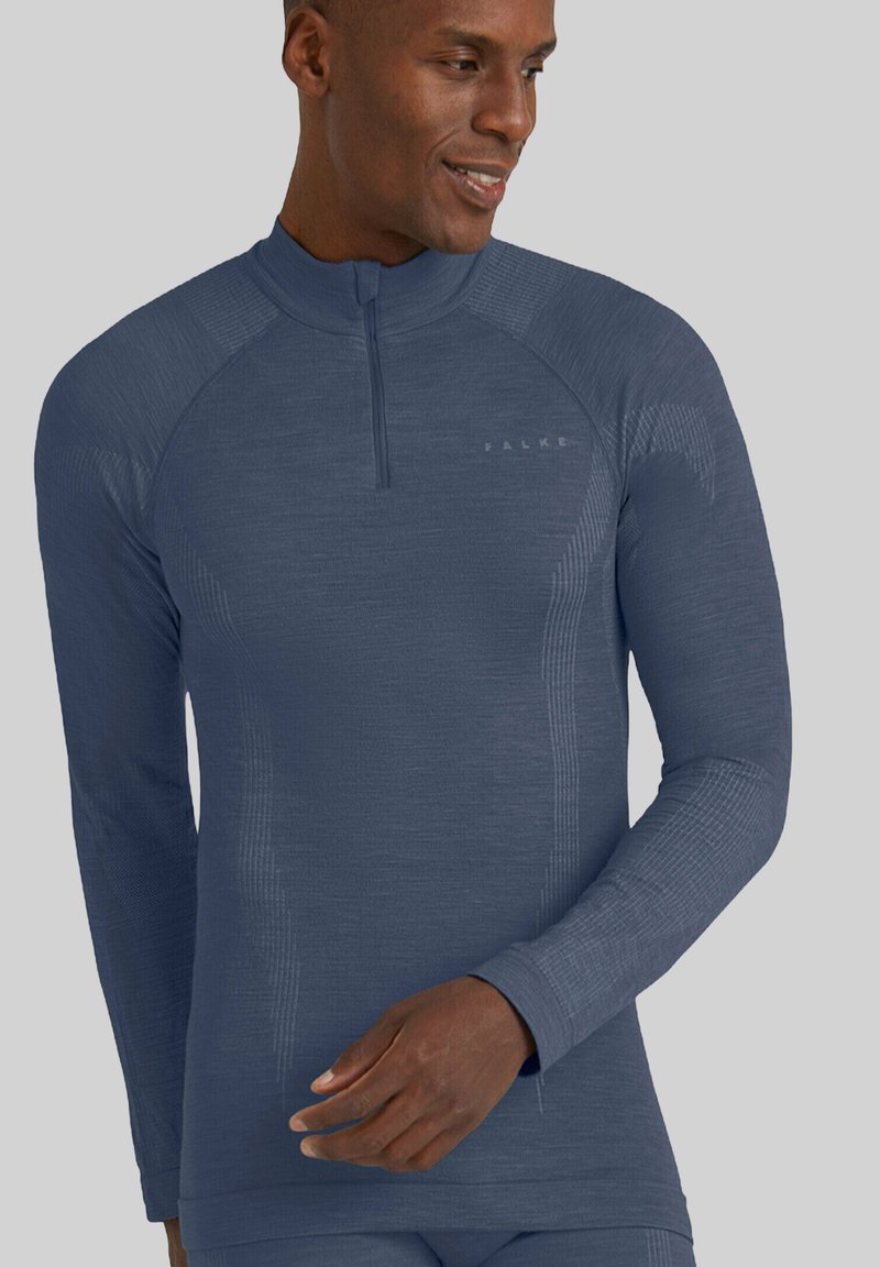 Długi rękaw sportowej bluzki w ciemnoniebieskim kolorze, wykonanej z teksturowanej tkaniny z półrozpinanym kołnierzem i subtelnymi wzorami. Posiada dopasowany krój.