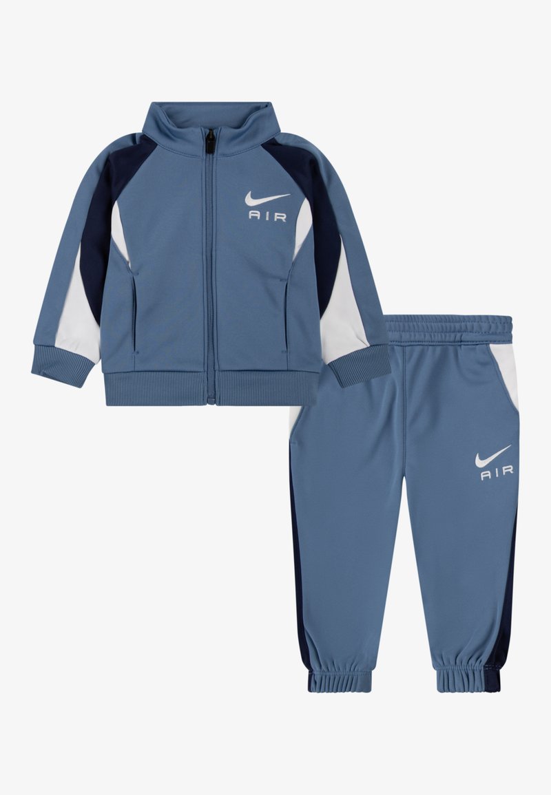 Blaue Nike Air børnetracksuit med jakke med lynlås og bukser med elastisk talje, prydet med hvide og mørkeblå farveblokke.