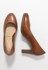 Scarpe con tacco alto in pelle marrone, con punta rotonda e tacco a blocco testurizzato, caratterizzate da una finitura liscia e una soletta imbottita.