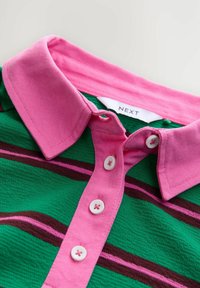 Green polo shirt with a pink collar, featuring horizontal brown and pink stripes and white buttons down the front. Brand label visible.