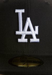 Casquette noire avec un logo "LA" brodé blanc. La casquette a un design structuré avec une visière plate et un tissu texturé. Étiquette de taille visible.