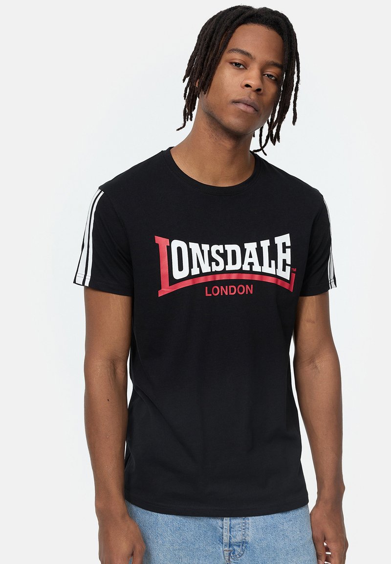 Melnas īsām piedurknēm T-kreklu ar baltu un sarkanu "LONSDALE LONDON" logotipu. Tam ir baltas svītras uz pleciem. Kokvilnas audums, parasta piegriezuma.