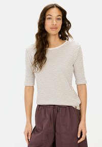 Gestreepte, lichtcrème en bruine top met driekwart mouwen en een ronde halslijn, gecombineerd met losse, donkerpaarse broek. Zachte textuur.