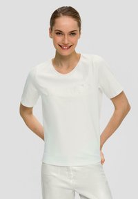 T-shirt blanc à manches courtes en tissu doux avec un col rond, présentant un design de texte en relief subtil à l'avant.