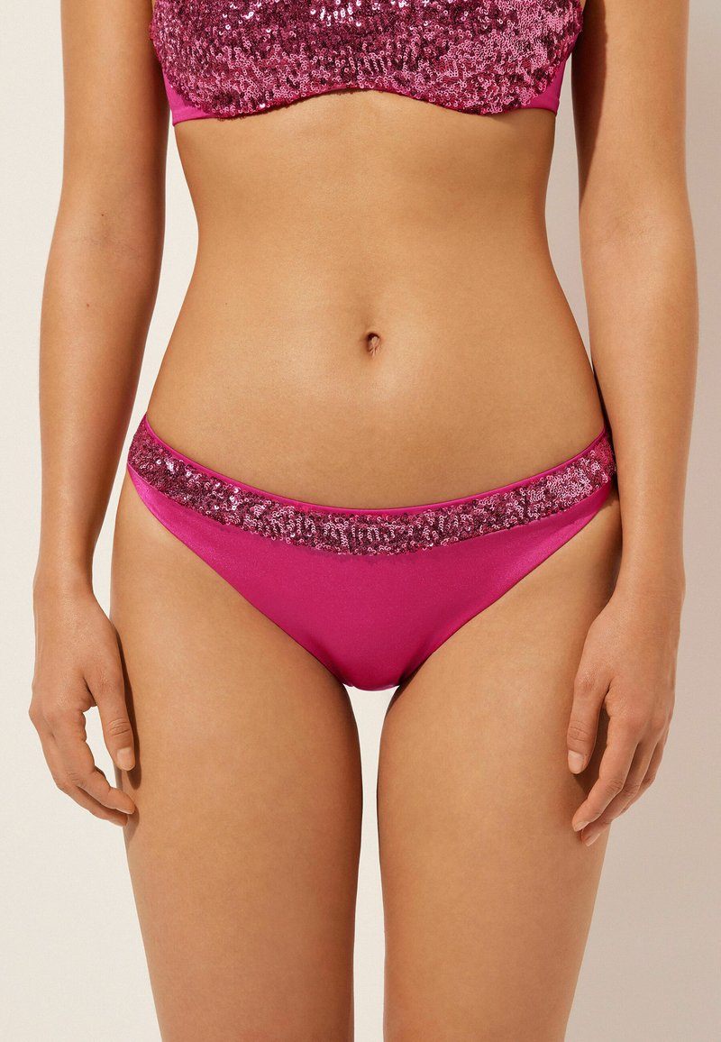 Rosa bikiniunderdelar med en blank texturerad midjeband prydd med paljetter. Tyget är slätt och i en enhetlig rosa färg.