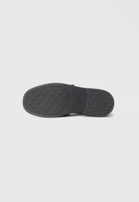 Black rubber shoe sole with textured grip pattern, featuring the brand name "ALDO" embossed on the side. Flat and rounded shape.