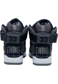 Ewing tenisky v tmavom námorníckom a šedém farebnom schéme. Obsahujú polstrovaný golier, suchý zips a bielu podrážku. Logo "Ewing" je výrazne zobrazené.