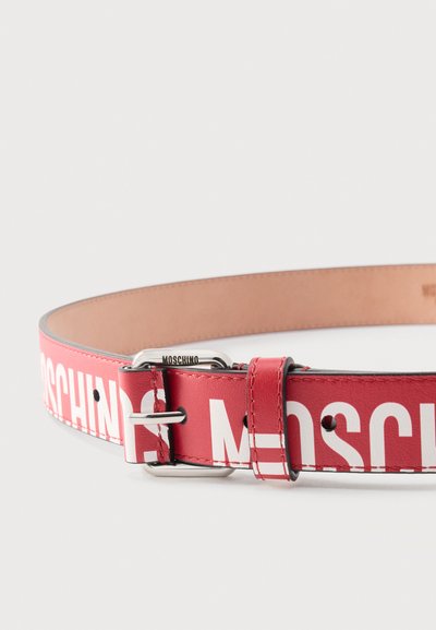 Κόκκινη δερμάτινη ζώνη με λευκό λογότυπο Moschino και ασημένια αγκράφα σε απλό φωτεινό φόντο.