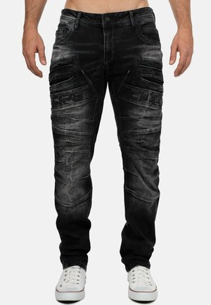 Black denim cargo pants with textured detailing, multiple side pockets, and faded finish. Features a button closure and reinforced seams.
