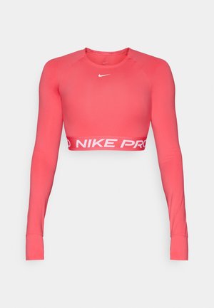 Top corto a maniche lunghe Nike Pro in un vivace color corallo, realizzato in tessuto elasticizzato. Presenta un collo rotondo e il marchio bianco "NIKE PRO" sull'orlo.