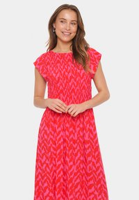 Robe maxi à motifs rouge et rose avec des manches courtes flottantes et une taille froncée, fabriquée en tissu léger.