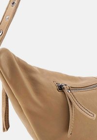 Borsa a spalla in pelle marrone con una texture morbida, forma curva e chiusura con zip laterale. Accentuata da hardware in tono argento e cuciture dettagliate.