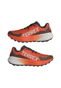 Raudoni ir juodi bėgimo bateliai su "TERREX" logotipu. Tinklinis viršus su tekstūruotu raštu, lengvas pado vidurys, guminis padas su sukibimu.