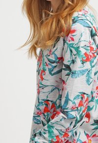 Top de manga larga gris con un estampado floral multicolor que incluye hojas rojas y azules; tejido suave y corte relajado, con cuello redondo.