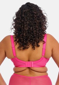 Roze beha met verstelbare schouderbanden en een haak-en-oogsluiting. Getextureerd materiaal met een gladde afwerking. Achteraanzicht, dat de rondingen en details onthult.
