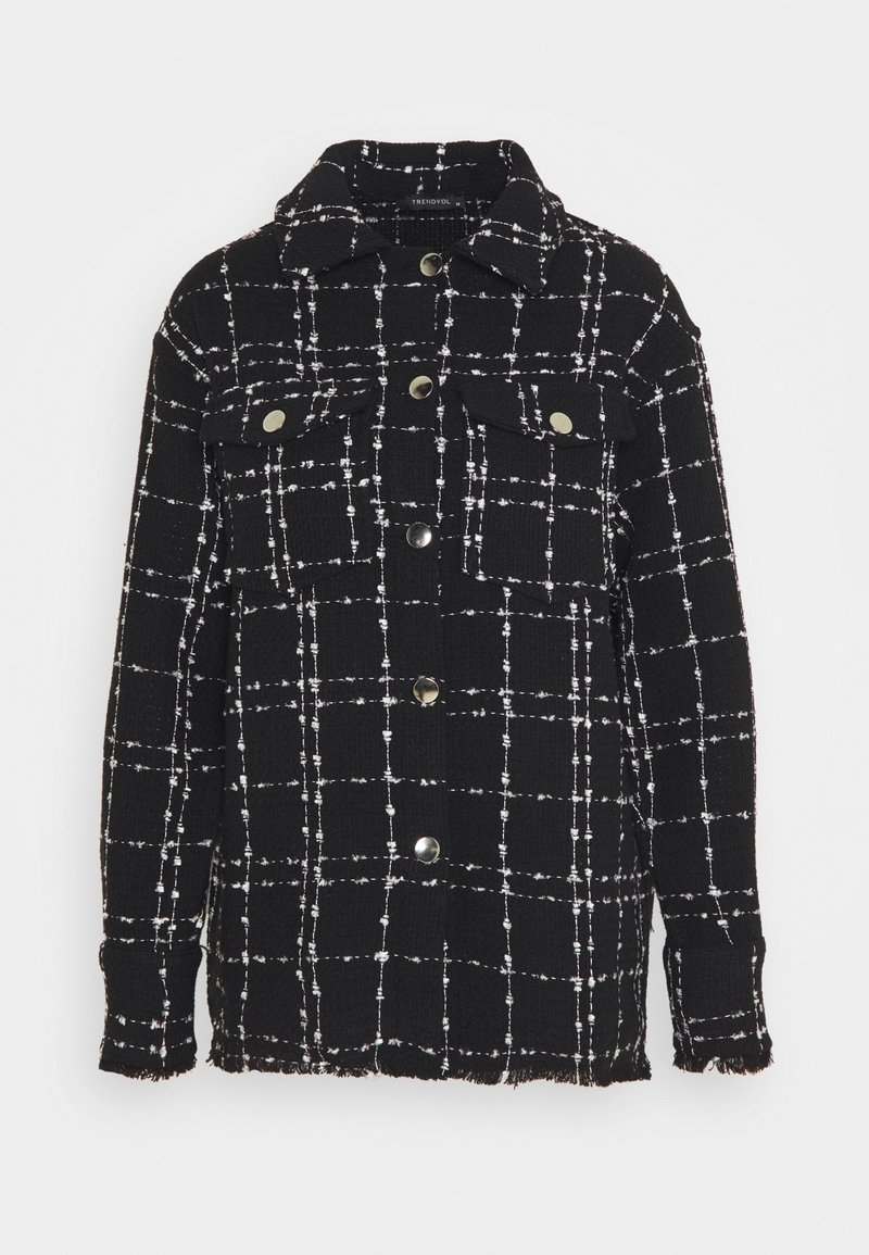 Veste noire à boutons avec motif à carreaux blanc, deux poches poitrine avec boutons, col, ourlet et poignets effilochés.