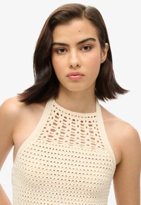 Crème haken haltertop met een gestructureerd open brei-ontwerp. Heeft een ronde halslijn en een aansluitende snit, ideaal voor zomeroutfits.