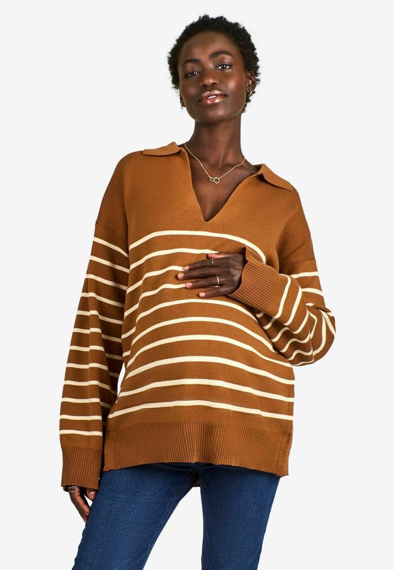 Pull marron à rayures avec un col en V, présentant de larges rayures crème, des manches larges et des poignets côtelés. Porté avec un jean bleu.